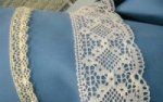 Broad and Narrow heritage lace on a roll of blue fabric